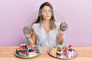 Young caucasian woman eating pastries for breakfast skeptic and nervous, frowning upset because of problem