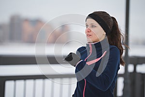 Young caucasian woman fitness model running at snow winter promenade, close up