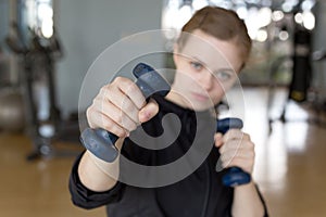 Young caucasian woman girl doing workout with light dumbbells at the gym, lifting weights