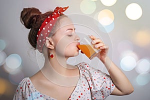 Young caucasian woman girl drinking a glass of orange or mango fruit juice or cocktail. Fresh summer party concept