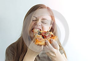 Young caucasian woman girl hungrily biting eating a slice of pizza with a funny face photo