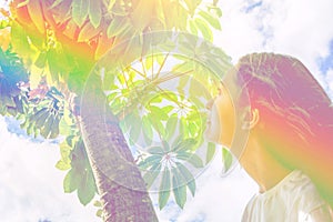 Young caucasian woman girl with long hair standing under tree looking up in the sky green foliage. Contemplation tranquility