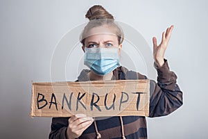 Young caucasian woman girl in mask holding banner bankrupt during coronavirus outbreak