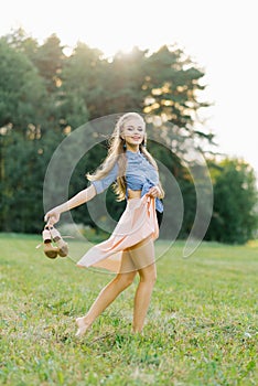 Young Caucasian woman or girl in a summer dress and a denim shirt is walking
