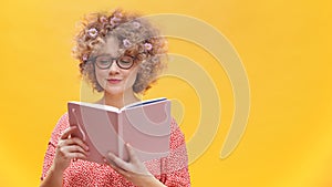 Young caucasian woman with glasses and flowers in curly hair reading a book. Spring concept