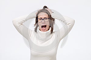 Young caucasian woman in glasses with shocked facial expression being amazed with news