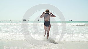 Young caucasian woman happily runs into sea water