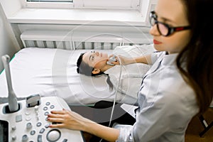 Young Caucasian woman having thyroind ultrasound test at female doctor`s office. Young Woman Doing Neck Ultrasound