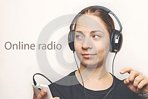 Young caucasian woman in headphones on head listening music Online Radio or podcast from mobile smartphone, digital entertainment