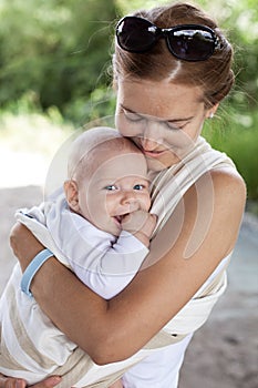 Young Caucasian woman and her baby son in sling