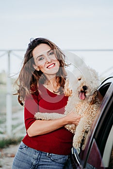 young caucasian woman with her poodle dog in a car. Travel concept. Lifestyle and pets