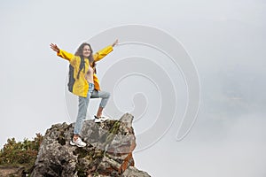 Young caucasian woman hiker on a rock against foggy background