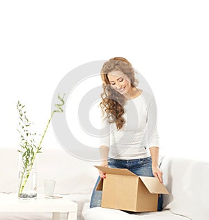 A young Caucasian woman holding a box on a sofa
