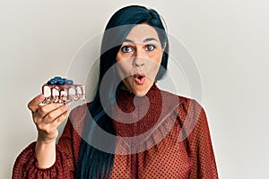 Young caucasian woman holding cake slice scared and amazed with open mouth for surprise, disbelief face