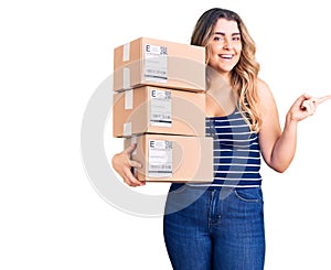 Young caucasian woman holding delivery package smiling happy pointing with hand and finger to the side