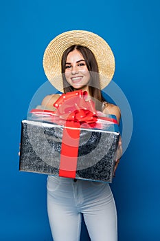 Young caucasian woman holding a gift box, smiling and looking at camera on blue background