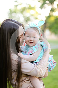 Young caucasian woman holding little daughter in green background.