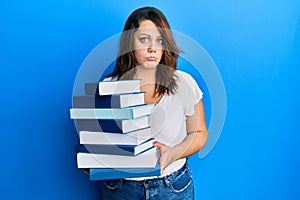 Young caucasian woman holding a pile of books depressed and worry for distress, crying angry and afraid