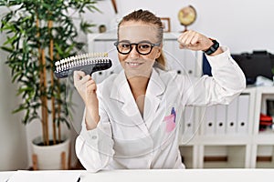 Young caucasian woman holding teeth whitening palette strong person showing arm muscle, confident and proud of power