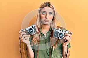 Young caucasian woman holding vintage camera depressed and worry for distress, crying angry and afraid