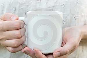 Young caucasian woman holding a white mug, mock up, blank space for text, artwork, hands, linen shirt