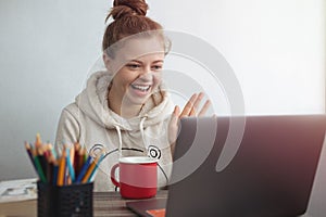 Young Caucasian woman with laptop at home making a video call, talking and smiling. Stay in touch with family concept