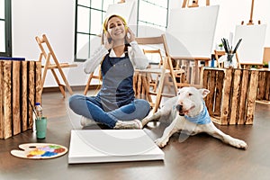 Young caucasian woman listening to music with dog at art studio