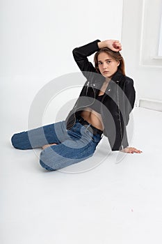 young caucasian woman with long brown hair in leather jacket on white background