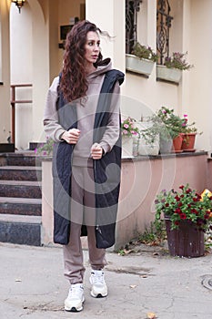 young caucasian woman with long curly brown hair in hoodie suit and dawn vest full body photo on mansion background