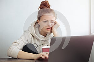 Young Caucasian woman looking bored in front of laptop at home. Work from home concept