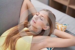 Young caucasian woman lying on sofa sleeping at home