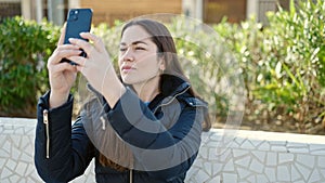Young caucasian woman make photo by smartphone with serious expression at park
