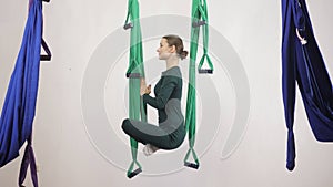 Young caucasian woman making antigravity fly yoga exercises in hammock in studio indoors. Aerial aero fly fitness