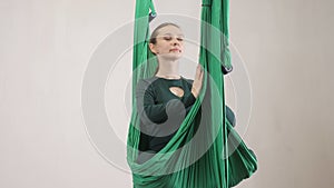 Young caucasian woman making antigravity fly yoga exercises in hammock in studio indoors. Aerial aero fly fitness