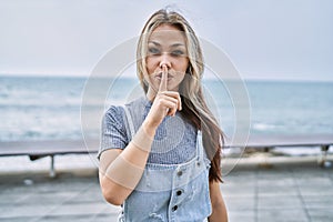 Young caucasian woman outdoors asking to be quiet with finger on lips