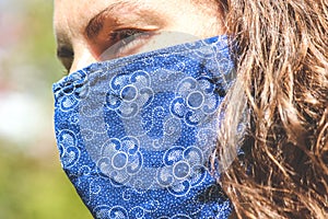 Young Caucasian woman outdoors with a blue fabric face mask during coronavirus pandemic. Coronavirus, COVID-19 outbreak. Virus