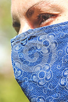 Young Caucasian woman outdoors with a blue fabric face mask during pandemic; COVID-19 outbreak. Virus