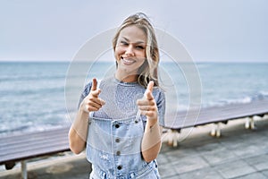 Young caucasian woman outdoors pointing fingers to camera with happy and funny face