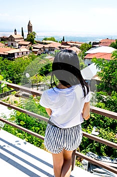 Young caucasian woman overlooks panoramic view of Sighnaghi