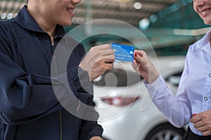 Young Caucasian woman paying via credit card to mechanic man in repair service shop