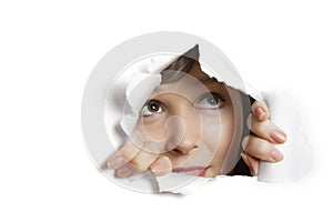 Young Caucasian woman peeking from ripped paper hole