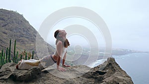 Young Caucasian woman performing upward facing dog pose outdoors