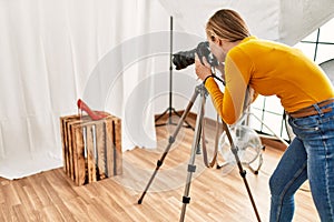Young caucasian woman photographer making photo to high heel shoe at photography studio