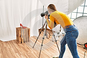 Young caucasian woman photographer making photo to high heel shoe at photography studio