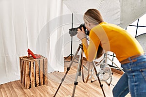 Young caucasian woman photographer making photo to high heel shoe at photography studio