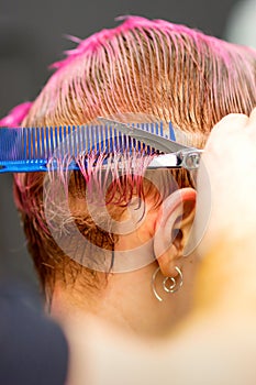 Woman with pink hair getting short haircut