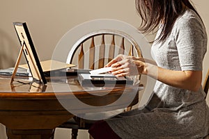 A young caucasian woman is placing a printed photograph into a picture frame with kickstand.
