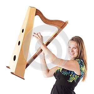 Young caucasian woman plays small harp in studio against white b