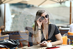 young caucasian woman in polka dot dress, watches and sunglasses close up photo in summer cafe
