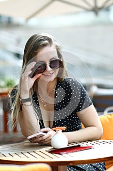 young caucasian woman in polka dot dress, watches and sunglasses close up photo in summer cafe